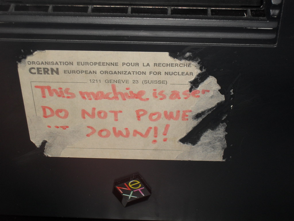 A heavily worn partially-removed sticker on a laptop. The header reads "CERN European Organization for Nuclear (...cut off)". There is a note written in marker reading "This machine is a ser(ver). DO NOT POWER (IT) DOWN!!